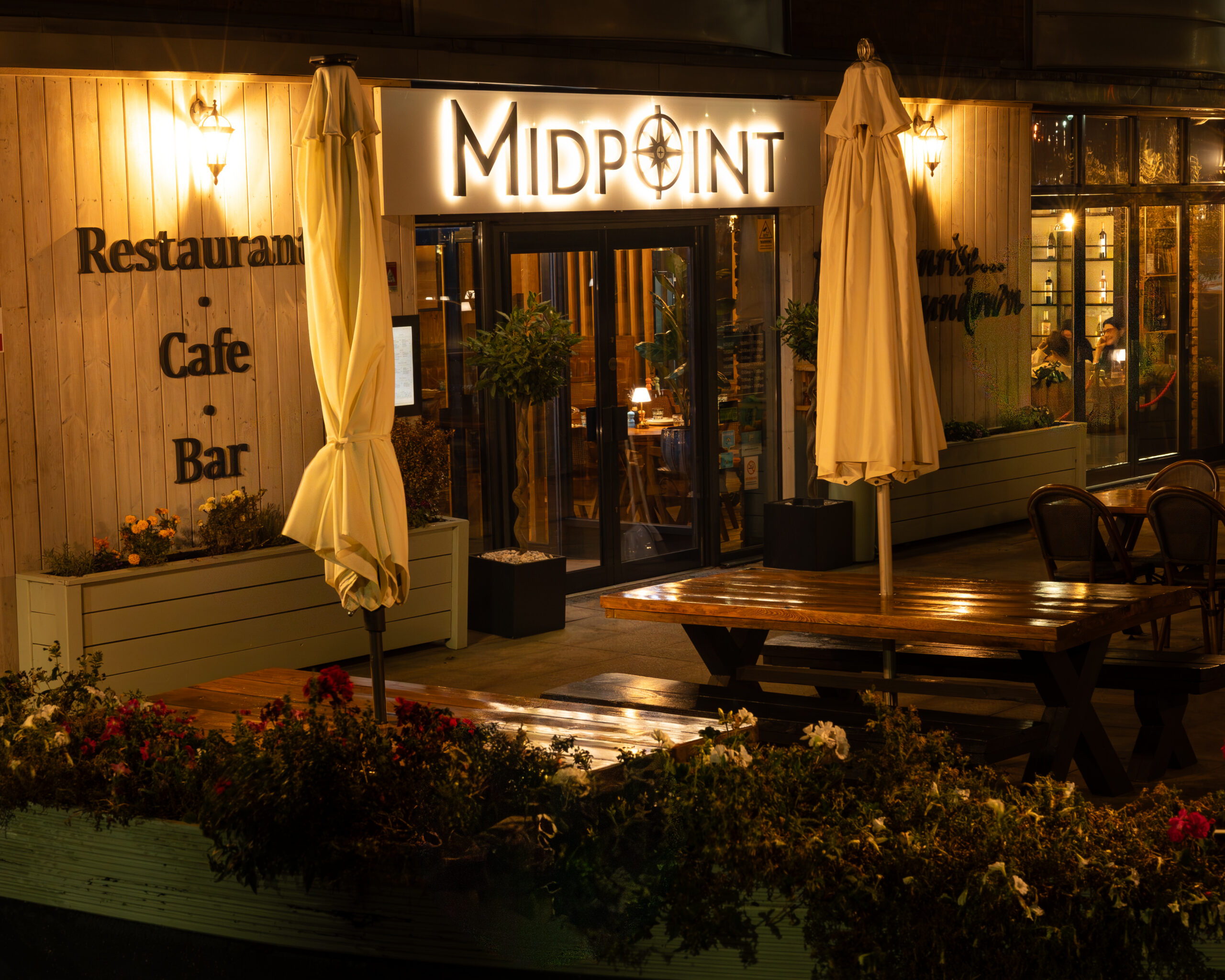 Midpoint Restaurant entrance and outdoor tables lit warmly in the evening.