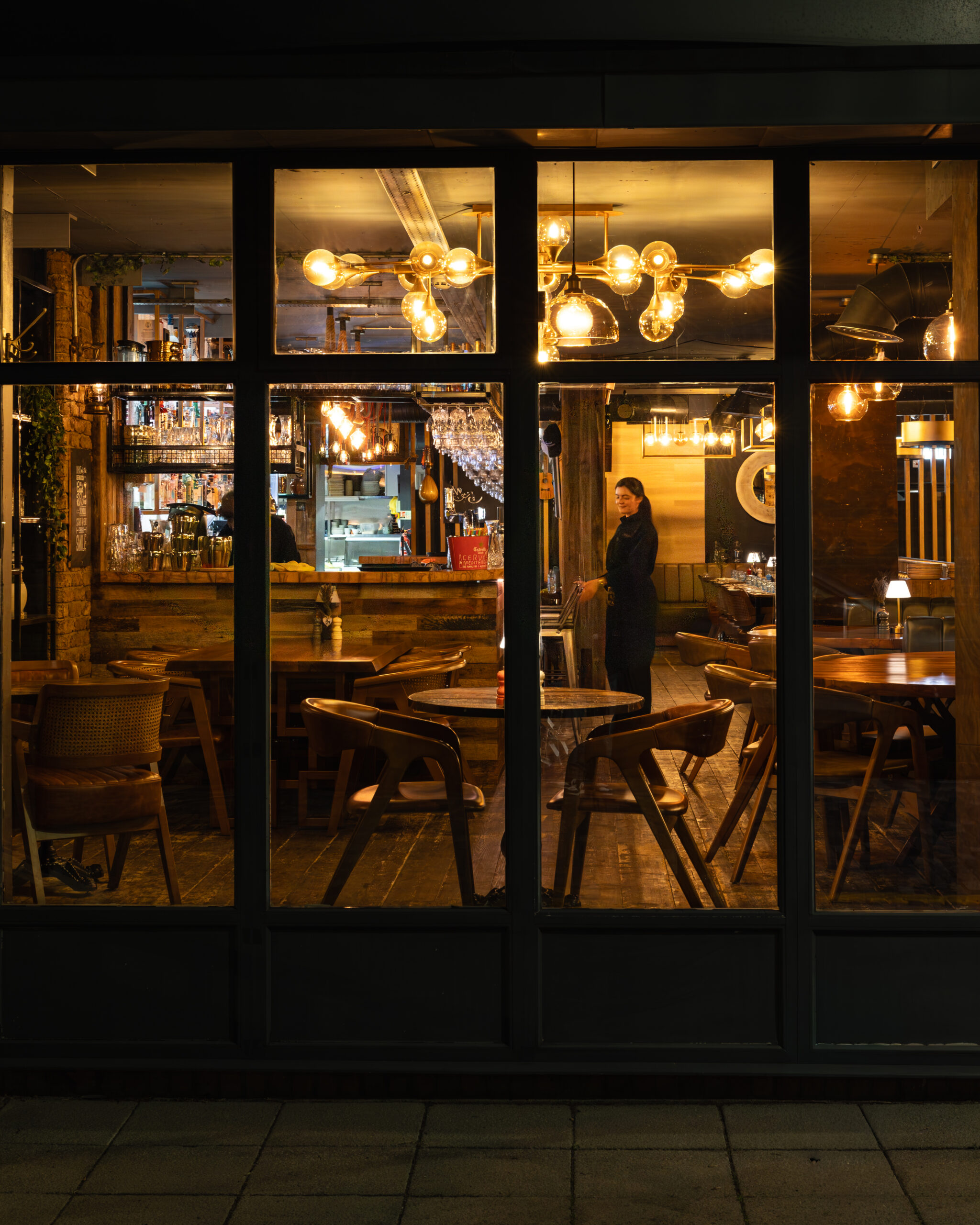 Warmly lit Midpoint restaurant interior seen through the front windows.