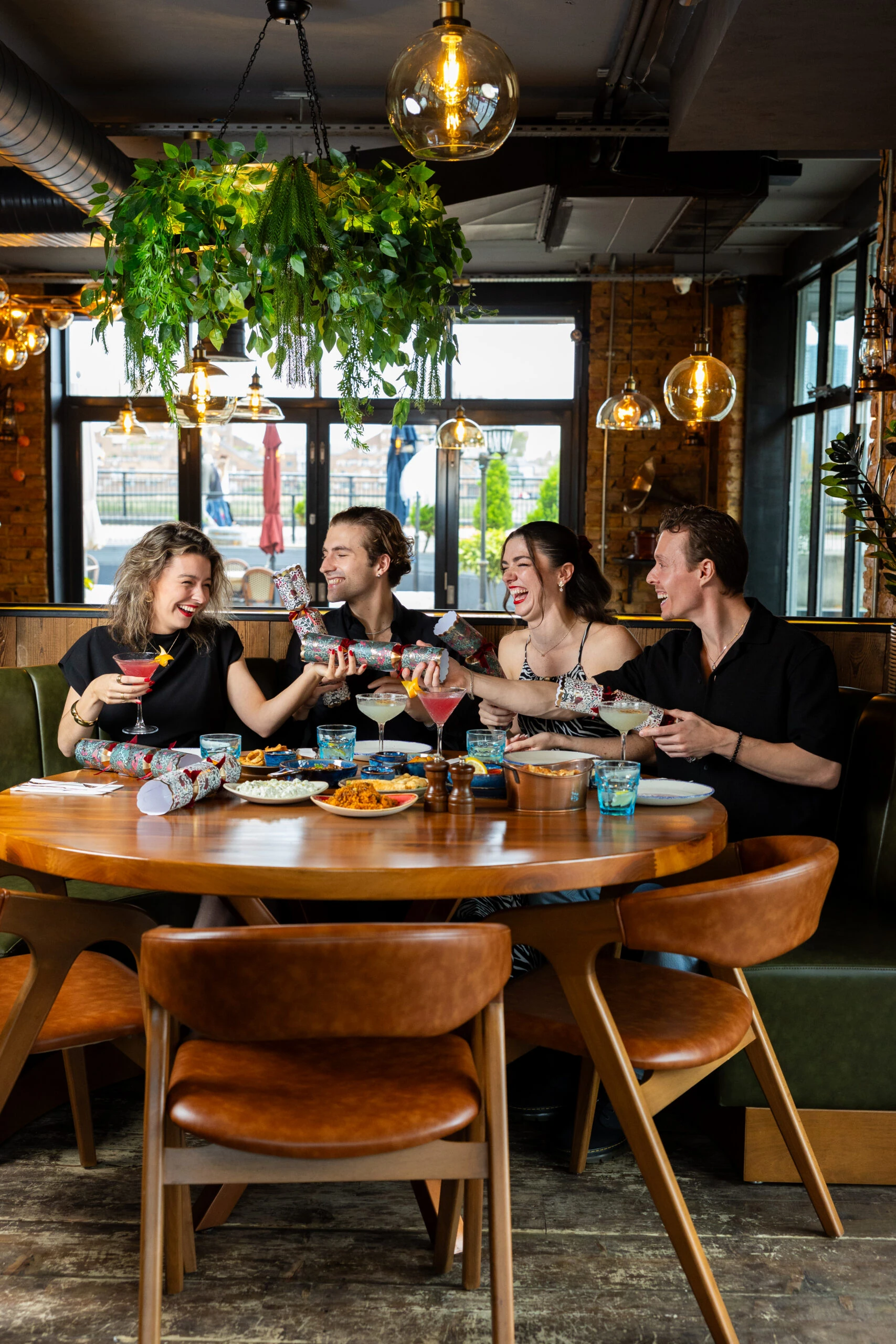 Friends sharing food and Christmas crackers around a festive table at Midpoint